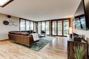 A spacious living room with a brown leather sofa, a coffee table, and a TV on a wooden cabinet. - Mid-Century Modern Retreat Near UO & Hayward Field (Eugene)