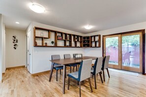 A dining area with a wooden table and chairs, a built-in shelf unit, and a sliding glass door leading to an outdoor patio. - Mid-Century Modern Retreat Near UO & Hayward Field (Eugene)