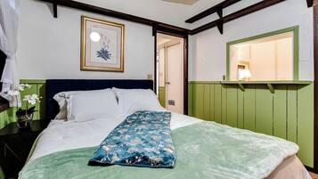 Quarto com cama, mesa de cabeceira, quadro emoldurado e espelho.