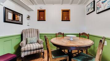 A dining area with a round wooden table, four chairs, a striped armchair, and a bench.