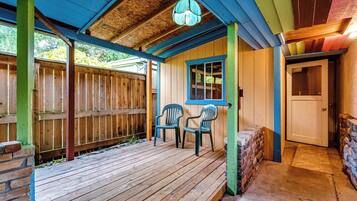 A wooden deck with two chairs, a door, and a window.