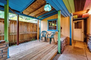 Eine Holzterrasse mit zwei Stühlen, einer Tür und einem Fenster.