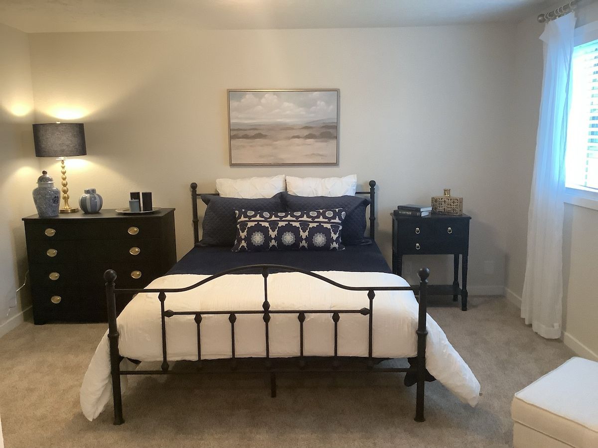 A bedroom with a bed, two nightstands, a lamp, and a painting on the wall.