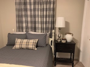 Ein Schlafzimmer mit einem Bett, Kissen, einem Nachttisch, einer Lampe und einer Vase.