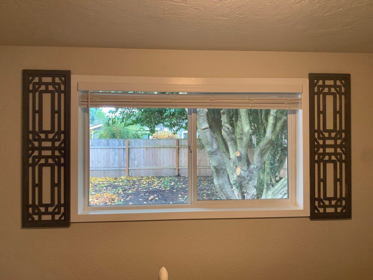 A window with a view of a tree and a wooden fence.