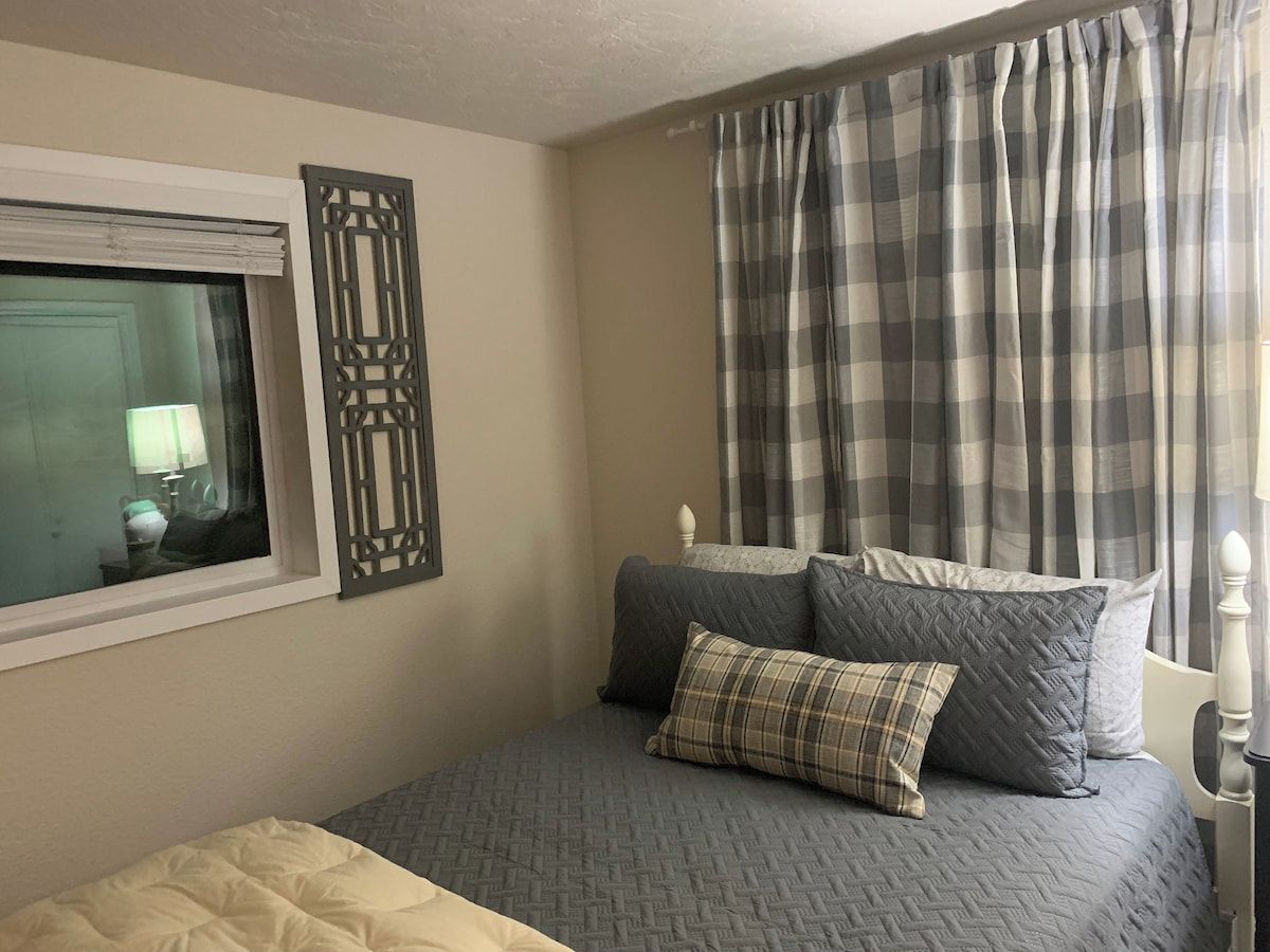 A bedroom with a bed, pillows, a window, and curtains.