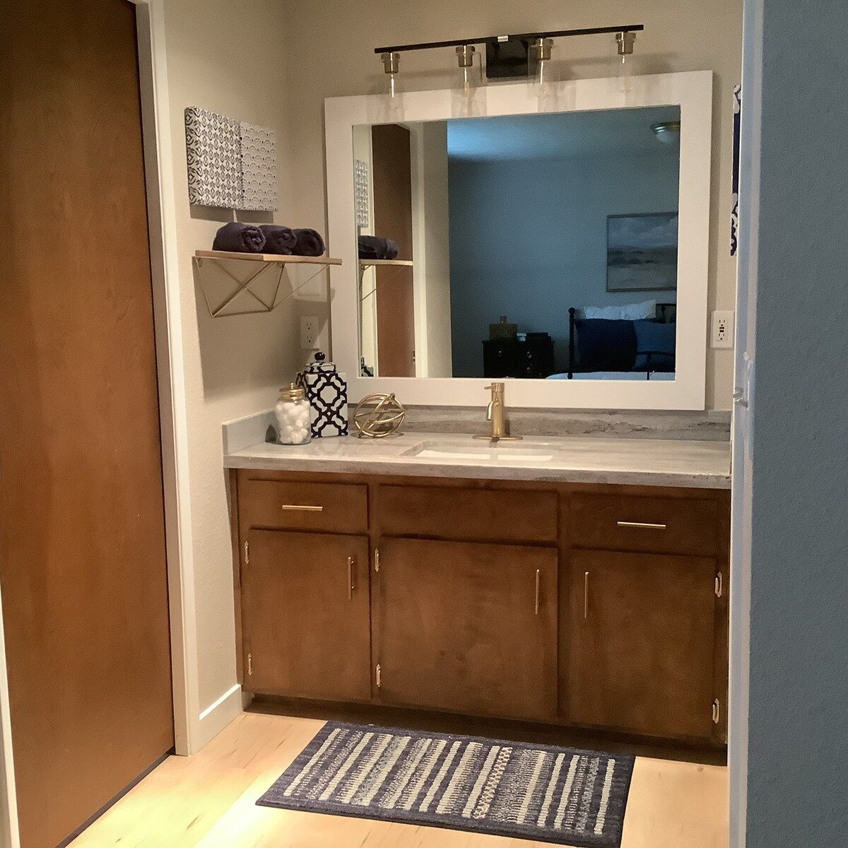 A bathroom with a large mirror, a sink, and a towel rack.
