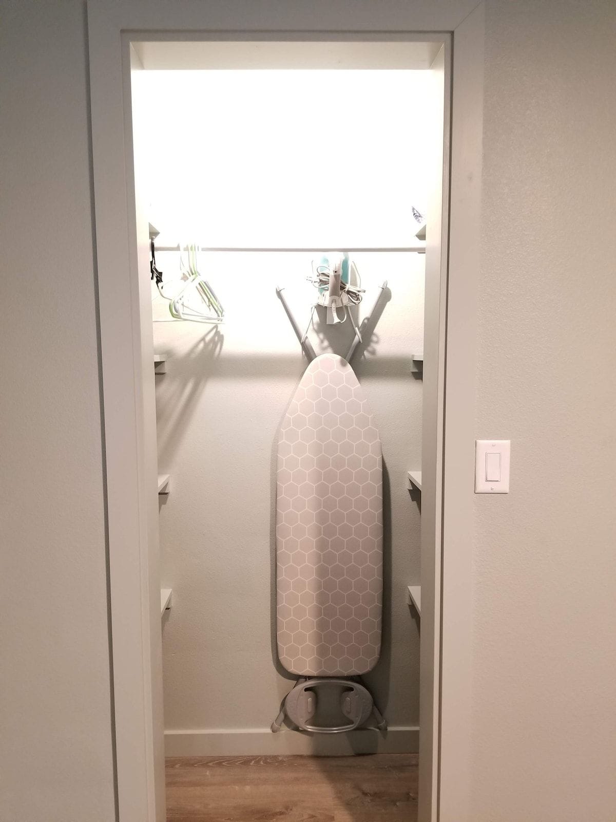 A closet with a hanging garment steamer and a metal rack with hangers.