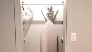 A closet with a hanging garment steamer and a metal rack with hangers.