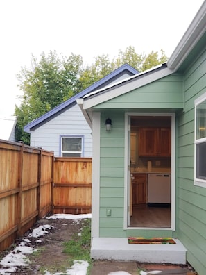 A small house with a green exterior, a wooden fence, and a visible kitchen area. - New Essential Location Home In The Heart Of Eugene (Eugene)