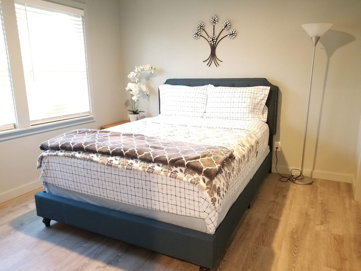 A bedroom with a bed, a wall-mounted light fixture, and a window with blinds.
