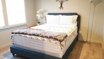 A bedroom with a bed, a wall-mounted light fixture, and a window with blinds.
