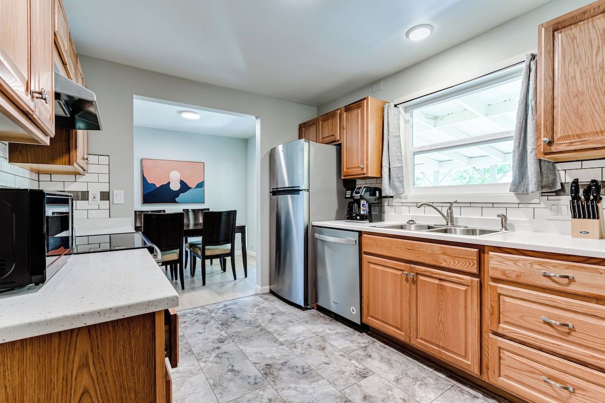 A modern kitchen with wooden cabinets, stainless steel appliances, and a dining area with a view.