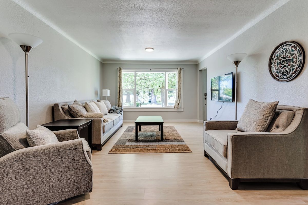 A living room with a sofa, armchairs, a coffee table, and a rug.