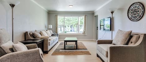 A living room with a sofa, armchairs, a coffee table, and a rug.