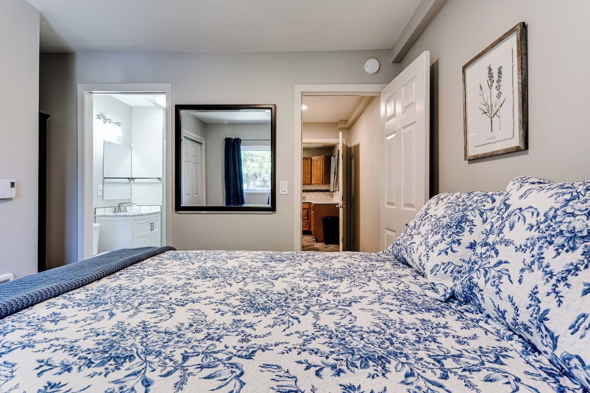 A bedroom with a bed, a mirror, and a door leading to a bathroom.