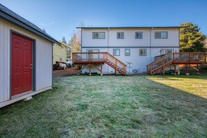A two-story building with a red door and a covered outdoor area with stairs. - West Hills Retreat with Reclining Couch & King Bed (Eugene)