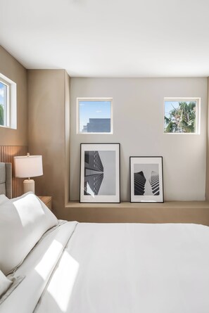 Habitación de hotel con una cama, una mesita de noche con lámpara y dos cuadros en la pared.