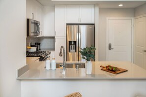 Una cocina moderna con electrodomésticos de acero inoxidable, una isla central con pileta y una puerta que da a otra habitación.