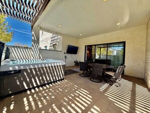 Une terrasse extérieure moderne dotée d’un jacuzzi, d’un espace salon et d’un téléviseur fixé au mur.