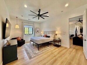 A modern bedroom with a bed, bedside tables, a desk, and a chair. - Hollow Sands Basecamp | Hot Tub | Pool | Fire Pit (Hurricane)