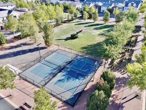 An aerial view of a residential area with a tennis court surrounded by trees and houses. - Hollow Sands Guest Suite | Hot Tub | Pool (Hurricane)