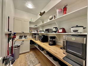 A modern kitchen with white cabinetry, a wooden countertop, and stainless steel appliances including a coffee maker and an oven. - Hollow Sands Retreat | Hot Tub | Pool | Duplex (Hurricane)