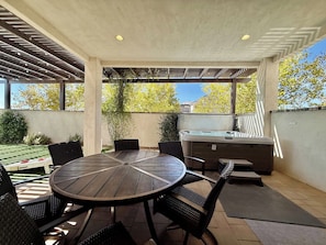 An outdoor patio with a round table and chairs, a hot tub, and a pergola structure. - Hollow Sands Retreat | Hot Tub | Pool | Duplex (Hurricane)