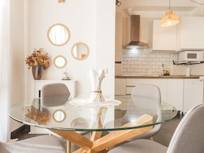A modern kitchen with white cabinets, a microwave, and a hanging light fixture. - Ladera Machin Apartment (Toledo)