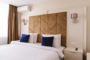 A hotel room with a large bed, two bedside lamps, a nightstand, and an air conditioning unit. - Hotel Belvedere (Eforie Nord)