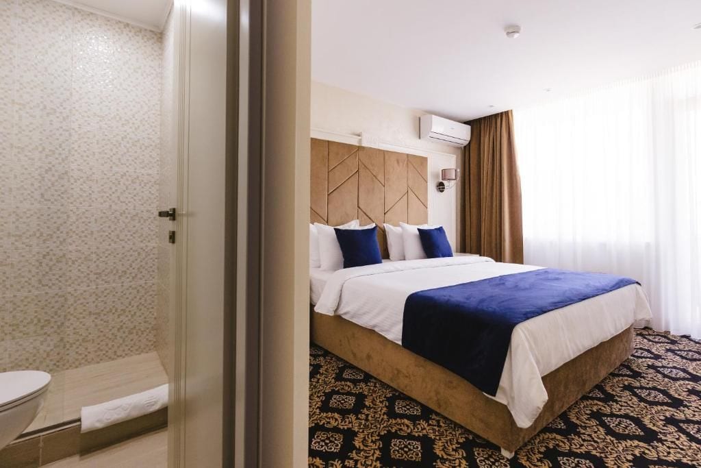 A hotel room with a bed, a bathroom, and a shower area.