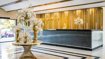 A reception area with a marble floor, a reception desk, and a decorative plant arrangement.