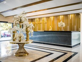 A reception area with a marble floor, a reception desk, and a decorative plant arrangement.