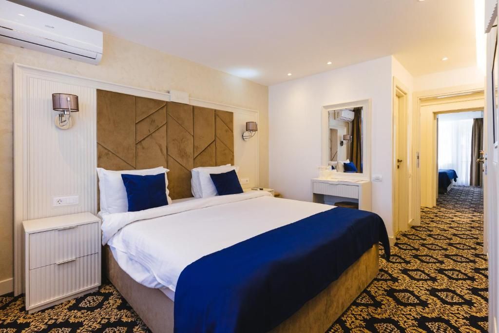 Habitación de hotel con una cama grande, mesitas de noche, un espejo y una alfombra estampada.