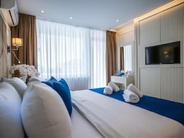 Una habitación de hotel con cama, televisión, escritorio y ventana con cortinas.