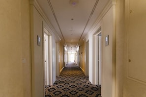 A hotel corridor with a patterned carpet, white walls, and doors on both sides. - Hotel Belvedere (Eforie Nord)