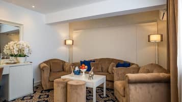 A modern living room with a beige sofa set, a white coffee table, and two side tables. There is a decorative bowl on the coffee table and a mirror on the wall.