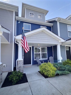 A two-story residential building with a front porch, a flag, and a small garden. - Nautilus Landing Getaway (Clarksville)