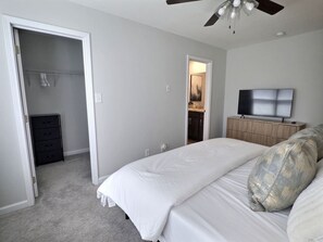 A bedroom with a bed, a television, a ceiling fan, and a wardrobe. - Nautilus Landing Getaway (Clarksville)