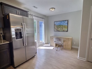 A modern kitchen with a stainless steel refrigerator, a water dispenser, and a sliding glass door leading to a balcony. - Nautilus Landing Getaway (Clarksville)