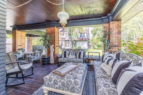 An outdoor covered patio with a brick wall, a wooden ceiling, and a hanging light fixture.