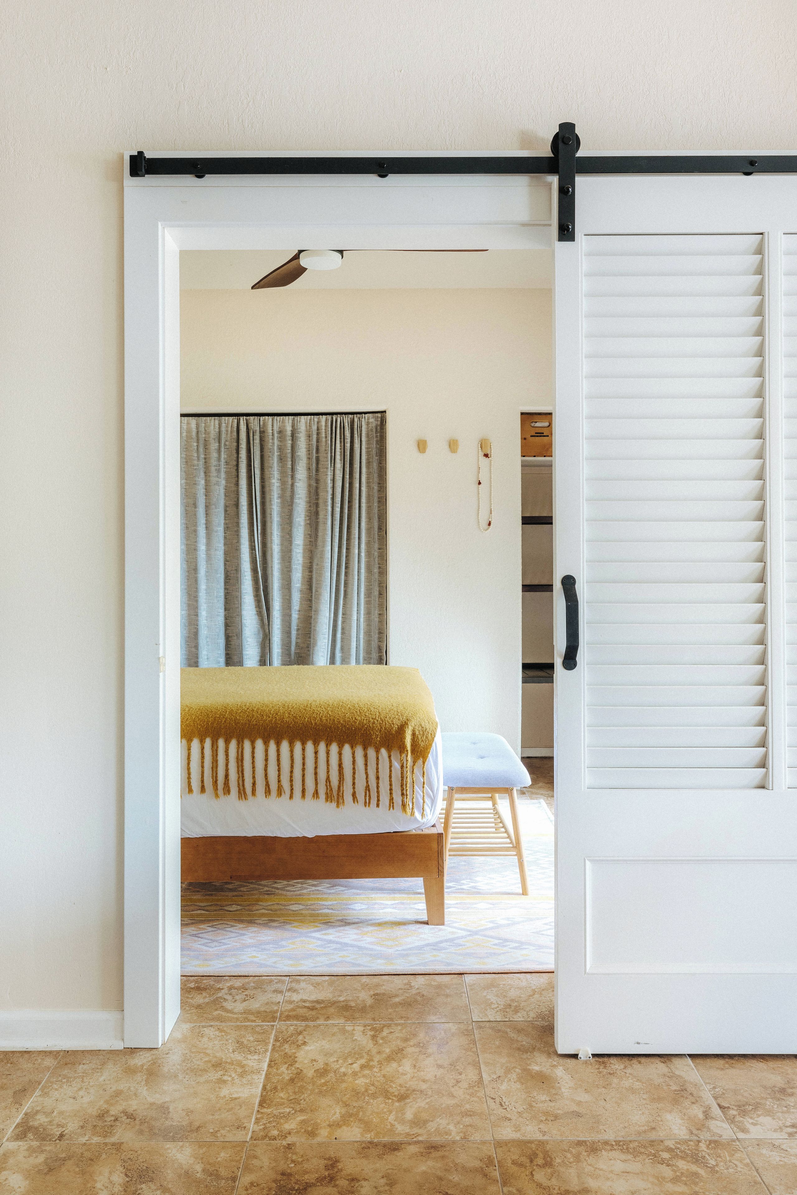 A bedroom with a bed, a bench, a wardrobe, and a door.