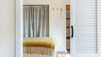 A bedroom with a bed, a bench, a wardrobe, and a door.
