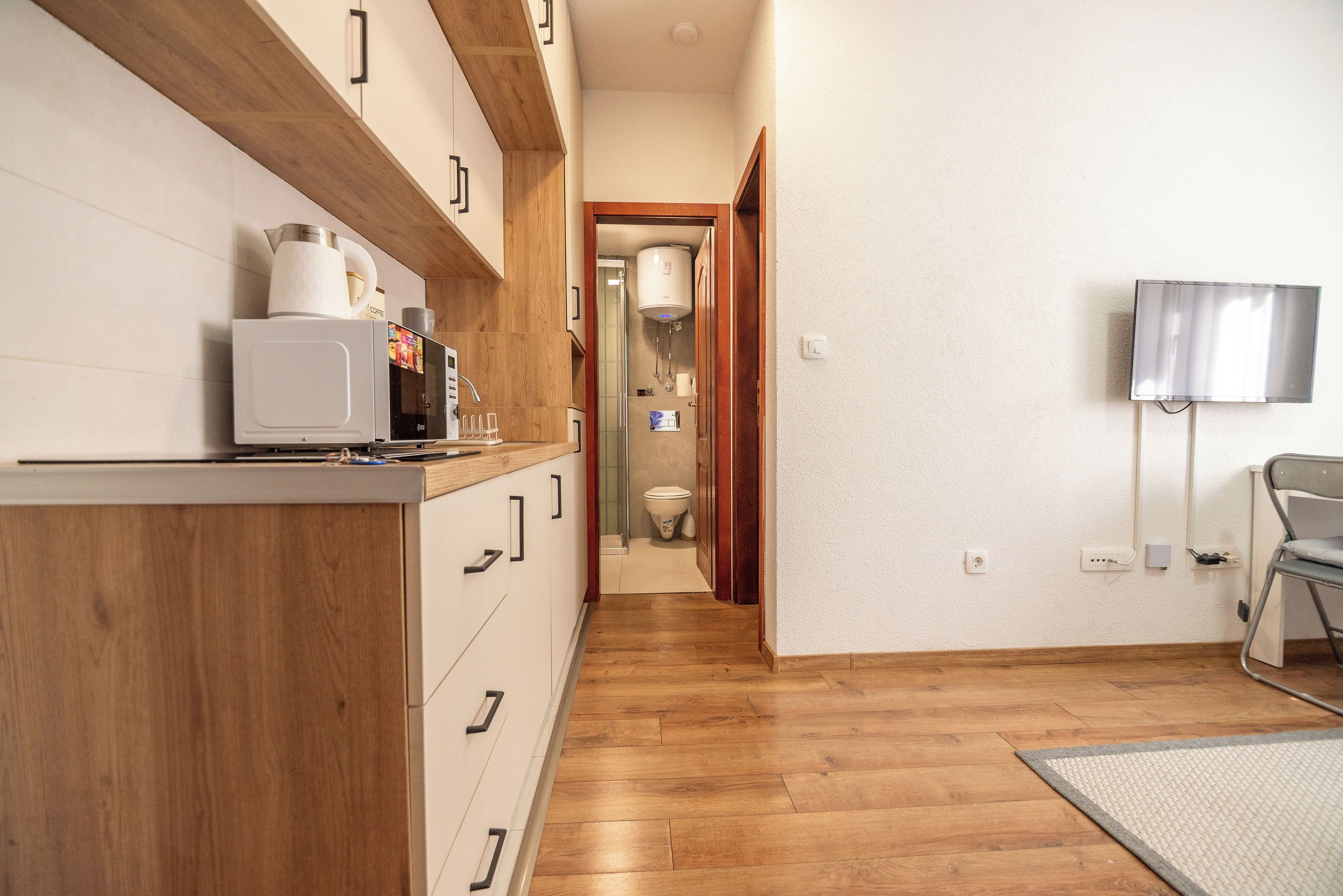 A compact kitchen with wooden cabinets, a microwave, and a coffee maker.