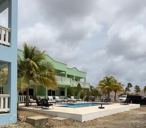 Ein Resort mit Swimmingpool, Liegestühlen und Palmen.