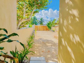 A paved pathway leading to a wooden gate, surrounded by greenery and a clear sky. - Perfect beachfront 3-bedroom house with AC in tranquil Chelem (Chelem)