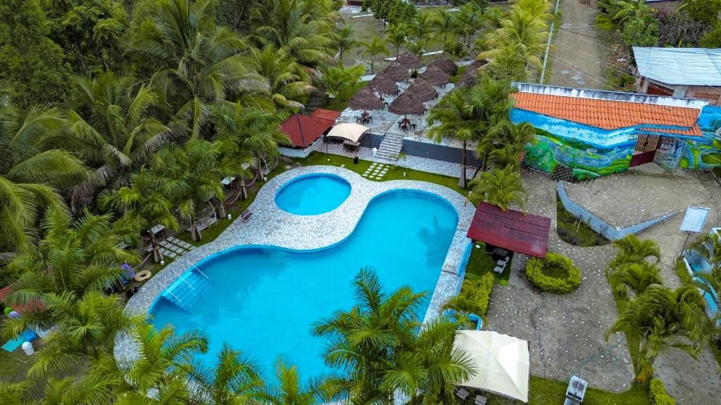 Uma grande piscina cercada por palmeiras e um edifício com telhado vermelho.