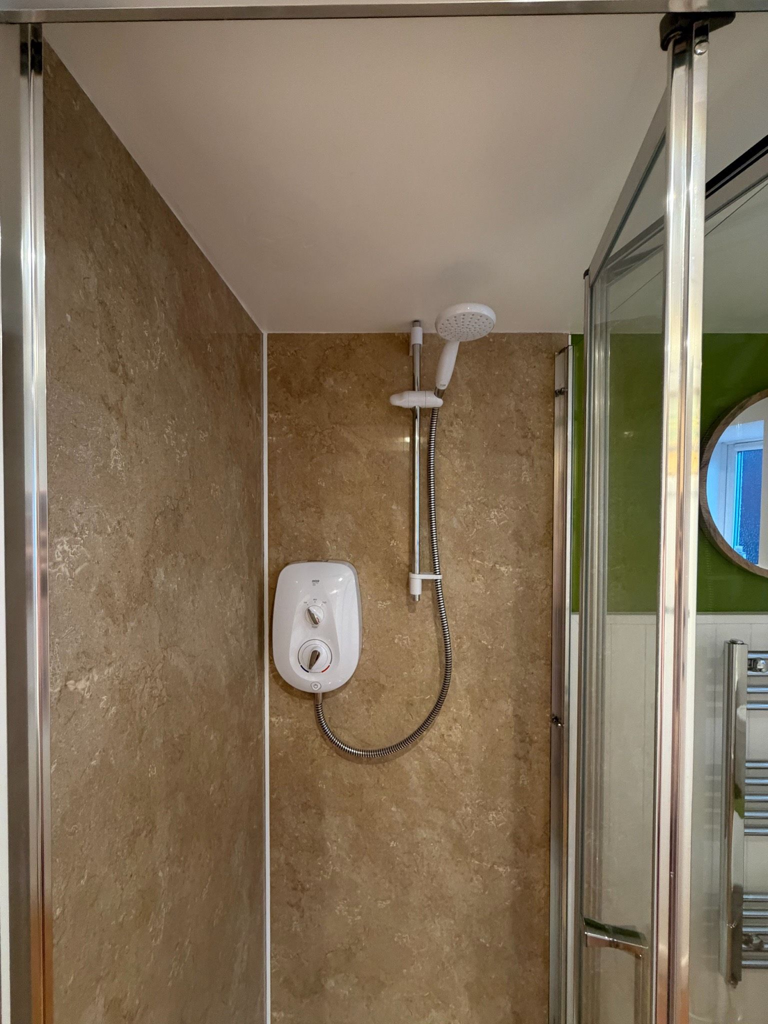 Une douche équipée d’un pommeau de douche à main et d’un panneau de commande fixé au mur.