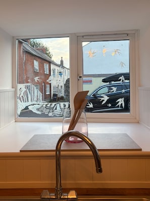 A window with a view of a street scene, including a black car and a building with a sign. - Walkersbase - Nutallergy Friendly - Stay3 - Petsok (Bridport)