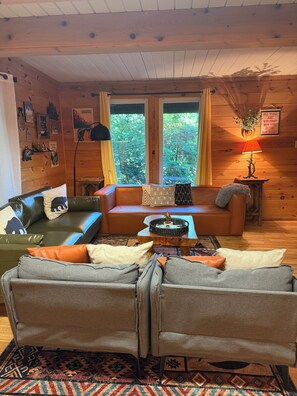 A cozy cabin interior with a leather sofa, a wooden coffee table, and a patterned rug. - Cozy Cabin Nestled on Infamous Ski Mountain Rd. (Gatlinburg)